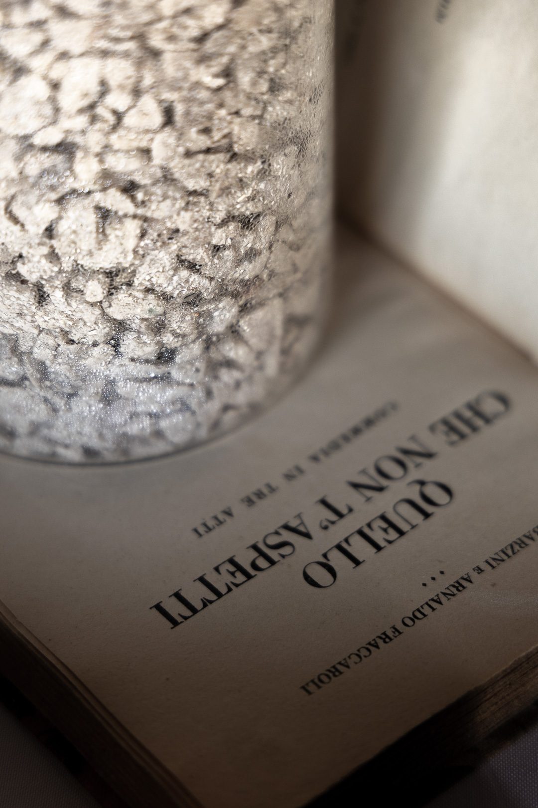 A candle burning beside the open title page of an old Italian play, Quello che non t'aspetti