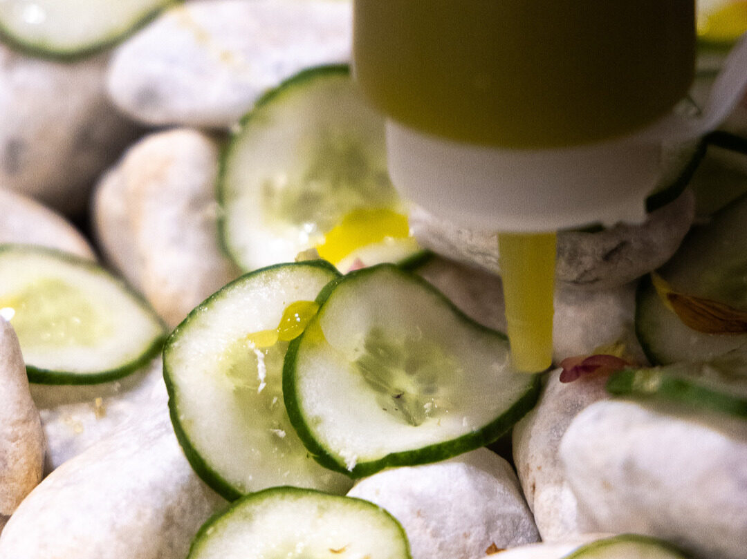Thin cucumber slices dressed with new olive oil among pale river stones